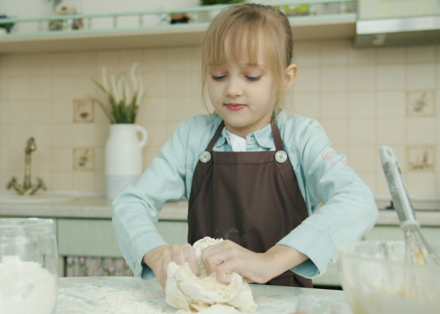 Ein Mädchen knetet Pizzateig